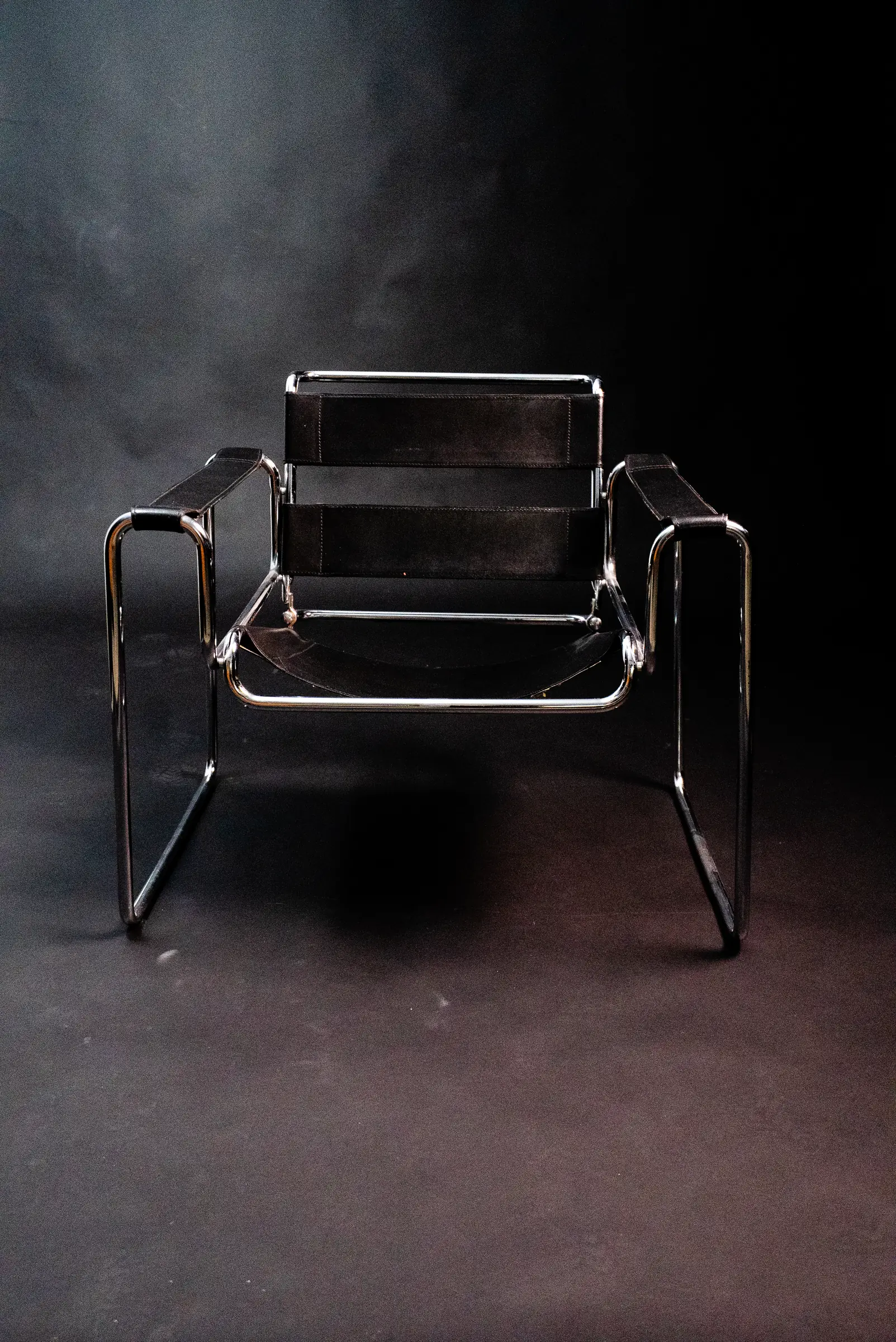 Une chaise en cuir et chrome sur le fond noir du studio photo, éclairée de face