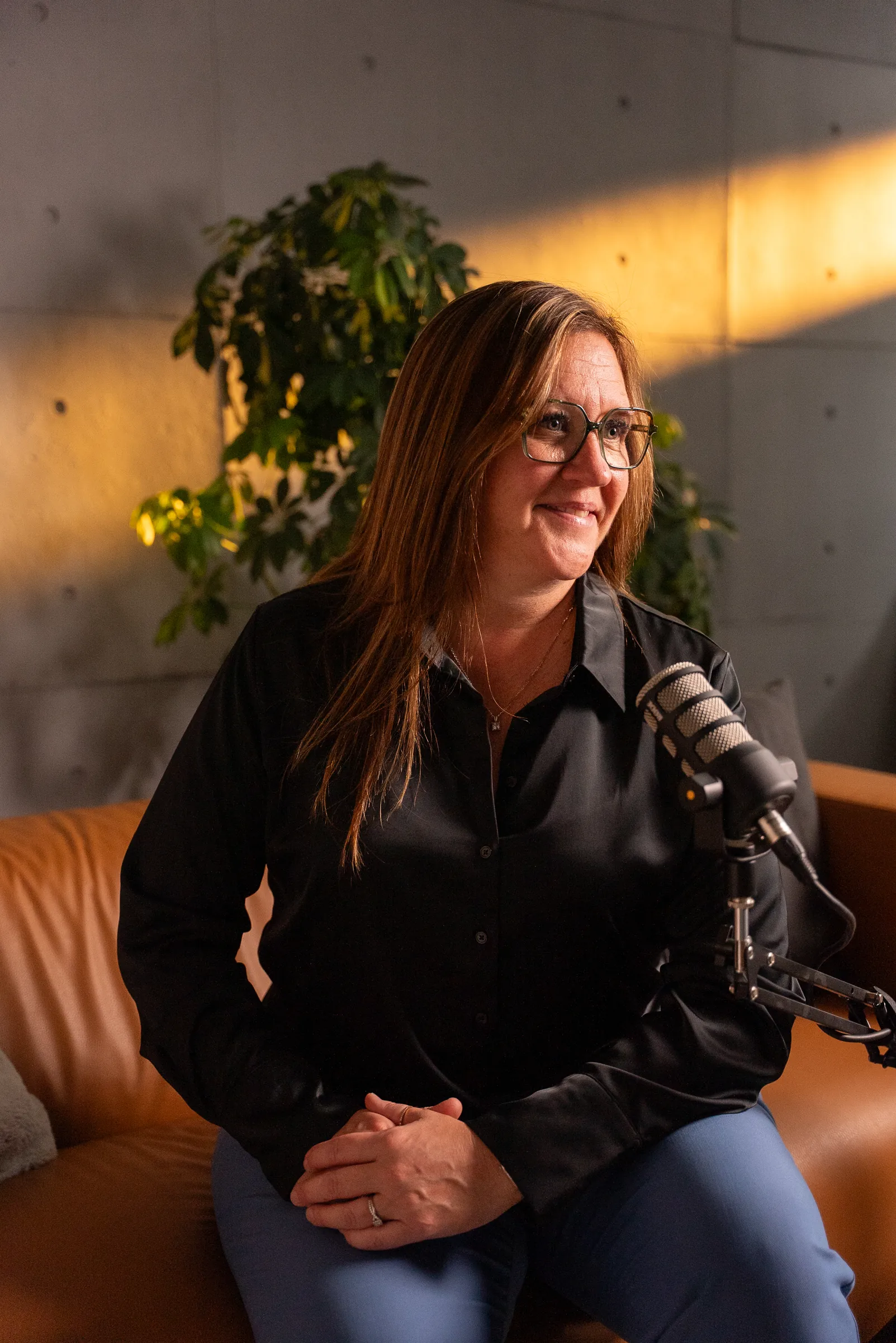 Une invitée parle au micro dans le studio podcast du Stoud, en lumière dorée