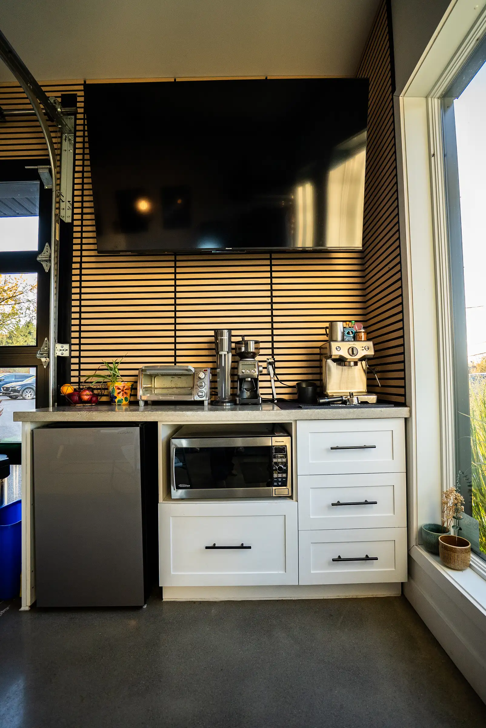 Le coin café de face : frigo, micro-ondes, machine espresso et télé