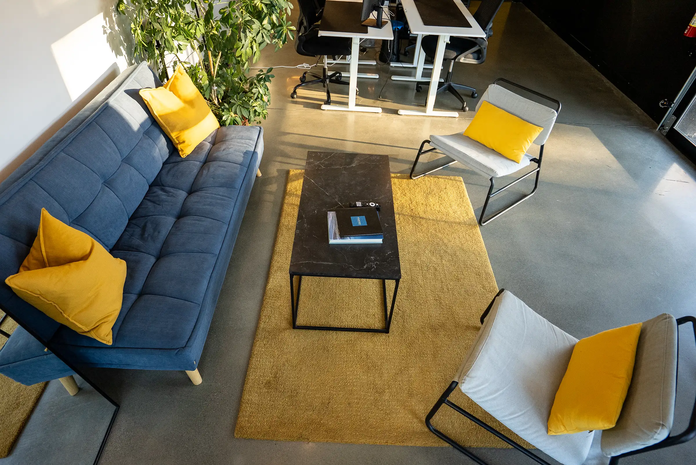 Le salon du Stoud vu d’en haut : divan bleu, deux fauteuils et tapis jaune