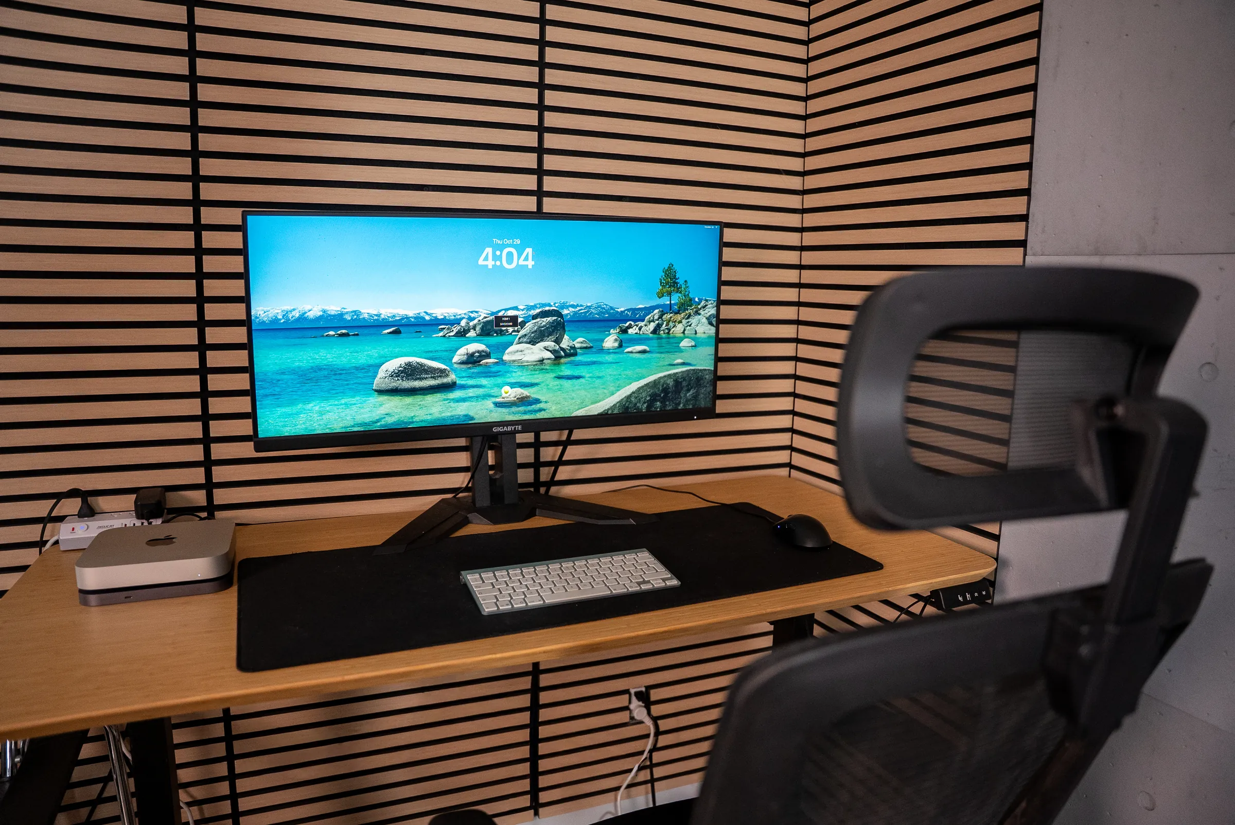 Le poste du bureau fermé : un Mac mini, un grand écran et un bureau en bois