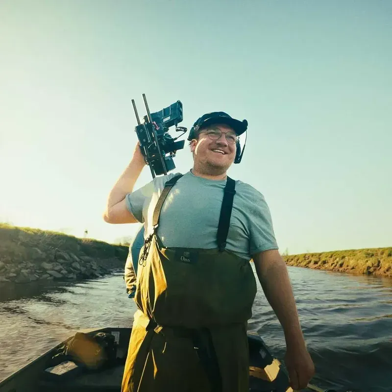 Alex Poirier, caméra à l'épaule, en tournage sur un bateau
